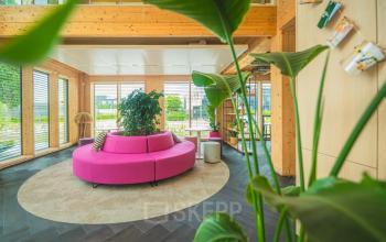Bright and modern office space at Moutlaan 1-23, Enschede, with bold pink seating and large windows offering natural light. Ideal for office space rental.