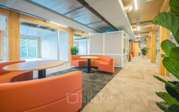 Warmly furnished office space with orange seating and modern decor at Moutlaan 1-23, Enschede, available for rent. Vibrant workspaces ideal for office space rental.