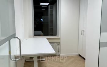 A modern, unfurnished office space with wooden flooring, a glass partition, and a large window, located in Enschede's Hoedemakerplein 2. Ideal for rent office space, offering a bright and inviting atmosphere.