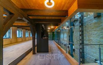 Interior view of an office space available for rent at Prins Hendrikkade 3, Franeker, showcasing a modern design with exposed beams and ample natural light.
