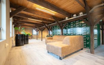 A cozy office space with wooden beams, a sofa, and a plant, available for rent at Prins Hendrikkade 3, Franeker.