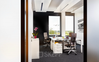Modernes Büro in der Solmsstraße 83, Frankfurt Bockenheim, mit stilvoller Einrichtung, zwei Schreibtischen und Blick auf einen startenden Flugzeug für effizientes Arbeiten. Perfekt für Büro mieten oder Büroraum mieten.
