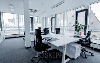 Großer Büroraum mit mehreren Arbeitsplätzen und großen Fenstern