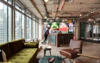 Moderne Büroräume in der Neue Mainzer Straße 66-68, Frankfurt Innenstadt, mit kreativer Einrichtung und Personen, die an der Rezeption stehen.