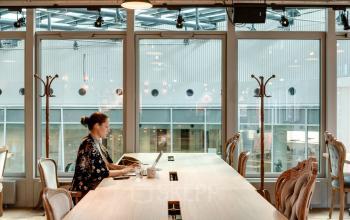 Person arbeitet an einem Laptop in einem modernen Büro mit großen Fenstern in der Neue Mainzer Straße 66-68, Frankfurt Innenstadt.