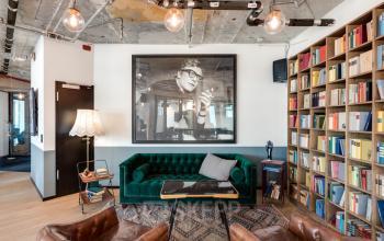 Gemütlicher Büroraum mit Sofa, Bücherregal und Kunstwerk an der Wand in der Neuen Mainzer Straße 66-68, Frankfurt Innenstadt.