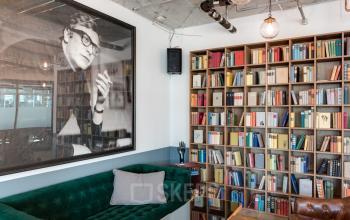 Gemütlicher Büroraum in der Neue Mainzer Straße 66-68, Frankfurt Innenstadt, mit Regalwand voller Bücher und grünem Sofa.