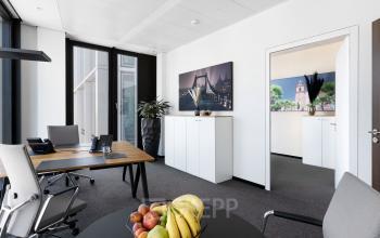 Büro in der Neue Mainzer Straße 6, Frankfurt Innenstadt, mit modernen Möbeln, großem Fenster und Dekorbildern an der Wand. Perfekt um ein Büro zu mieten.