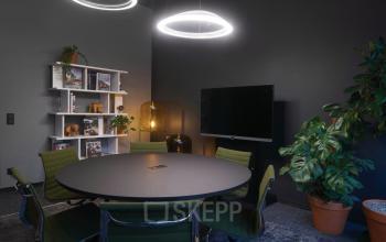 Moderner Besprechungsraum in der Barckhausstraße 1 in Frankfurt Westend mit rundem Tisch und grünen Stühlen. Bürofläche mieten.