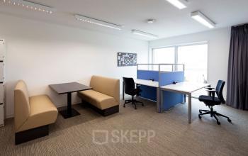 Bright office space available for rent at Transportlaan 1-151, Geleen, featuring cushioned booths and workstations with natural light.
