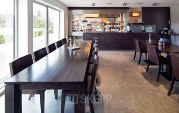 Spacious and bright cafeteria-style workspace at Transportlaan 1-151, Geleen, perfect for office space rental. The room features a long table, chairs, and large windows for natural light.