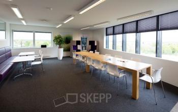 Bright and furnished office space with large windows and several tables at Transportlaan 1-151, Geleen. Ideal for those seeking office space rental.
