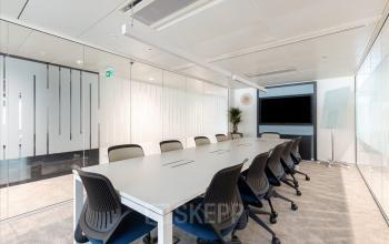 Modern gestalteter Konferenzraum zum büroraum mieten im Esplanade de Pont-Rouge 4, Genf Grand-Lancy mit langem Tisch, Stühlen und Präsentationsscreen.