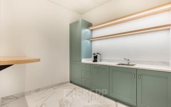 Modern gestaltete Büroküche in Genf Innenstadt, Place de la Fusterie 12, mit hellen Oberflächen und grünen Schränken, ideal zum büroraum mieten.