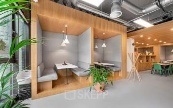 Innenansicht eines modernen, möblierten Büroraums in der Rue de Lausanne 15, Genf Innenstadt, ideal zum Büro mieten. Zwei Sitznischen und ein offener Arbeitsbereich sichtbar.