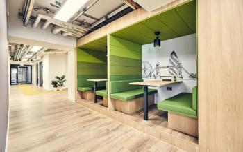 Bürofläche mieten in der Rue de Lausanne 15, Genf Innenstadt. Moderne, möblierte Arbeitsnischen mit grün gepolsterten Sitzgelegenheiten und Holzelementen.