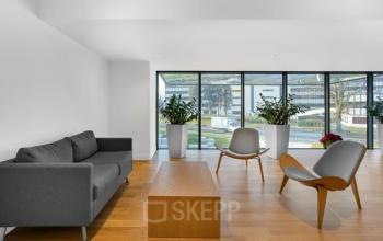 Ein moderner Empfangsbereich in einem Bürogebäude in der Rue du Pré-de-la-Bichette 1, Genf Les Genets, Genf, mit Sitzecke und großen Fenstern.