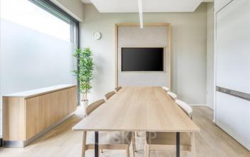 Heller Besprechungsraum mit Holztisch, Stühlen und Bildschirm für Präsentationen im Büro in Route de Pre-Bois 14, Genf Meyrin.
