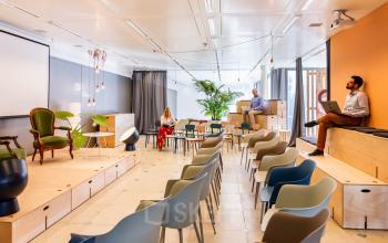 Moderne Bürofläche mieten in Genf Vernier, Route de Meyrin 123; ein Raum mit Stühlen, Bühne und drei geschäftstätigen Personen.