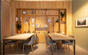 Modern kantoorruimte te huur op Gaston Crommenlaan 8, Gent Ledeberg, met houten bureaus, verlichting, boekenplanken en planten.