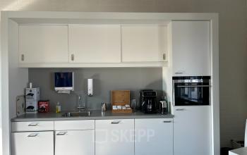 Office pantry area at Techniekweg 15, Gorinchem with modern white cabinets, a sink, coffee machine, and microwave. Suitable for tenants using the office space rental.