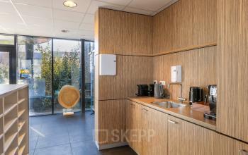 Furnished office kitchen area with wooden cabinets and several coffee machines at Techniekweg 15, Gorinchem. A modern space suitable for rent office space enthusiasts.