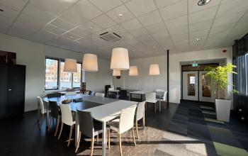 Bright office space with modern furnishing, large windows, and ample lighting at Techniekweg 15, Gorinchem. Perfect for office space rental, well-equipped with tables and chairs for collaborative work.