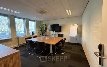 Conference room at Techniekweg 15, Gorinchem, featuring a wooden table, modern chairs, a TV, a flip chart, and large windows.
