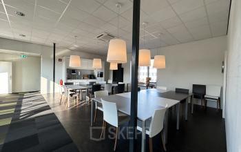 Modern furnished office space with tables and chairs at Techniekweg 15, Gorinchem, featuring overhead lighting and a clean, bright atmosphere.