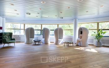 Bright office space rental at Groningenweg 8 8, Gouda, featuring unique seating pods and a leafy plant, ideal for quiet work sessions.