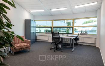 Furnished office space for rent at Groningenweg 8 8, Gouda, featuring a modern workspace with a desk, chair, and large windows offering natural light.