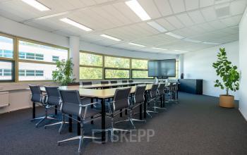 Bright office space meeting room at Groningenweg 8 8 in Gouda, featuring a long table with several chairs and large windows providing natural light, available for office space rental.