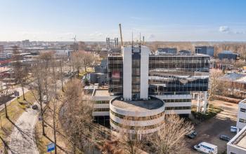 Exterior view of the office building at Groningenweg 8 8, Gouda, available for office space rental. The building is surrounded by trees and neighboring buildings.