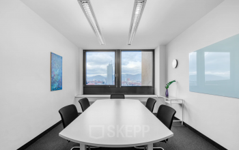 Spacious conference room available for office space rental at Brückenkopfgasse 1, Graz, with a large window offering city views.