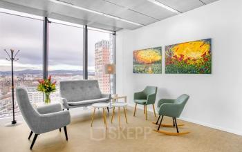 Office space rental with stylish seating area, large windows, and art in Graz at Brückenkopfgasse 1.