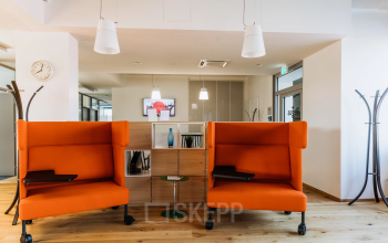 Modern office space rental at Waagner-Biro-Straße 47, Graz, featuring bright orange couches and a neat, professional layout.