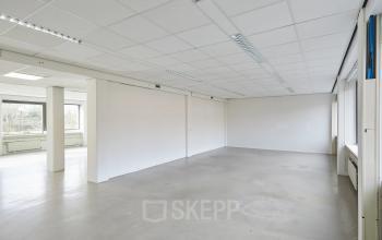 Spacious office space available for rental at Schweitzerlaan 12, Groningen, featuring a bright interior with large windows and neutral walls.