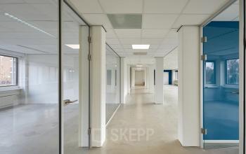 Interior view of Schweitzerlaan 12, Groningen, showcasing a bright and spacious office space rental with large windows and multiple glass-walled rooms for workspaces.