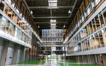 Modern office space with high ceilings and spacious design at Helperpark 270-298 in Groningen. Bright green flooring and ample natural light enhance the vibrant work environment, ideal for office space rental.