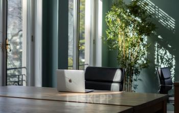 Spacious office space rental at Kennemerplein 20, Haarlem Centraal Station, featuring a modern desk with a laptop and a comfortable chair with natural light.