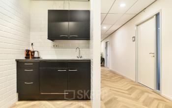 A well-equipped pantry in the office space rental at Kennemerplein 20, Haarlem Centraal Station, featuring modern black cabinets and appliances.