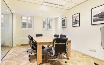 Elegantly furnished office space rental at Kennemerplein 20, Haarlem Centraal Station, with a polished wooden table and comfortable chairs.