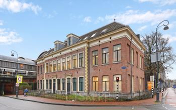 Elegant office space rental within the historic facade of Kennemerplein 20, near Haarlem Centraal Station, under a clear blue sky.