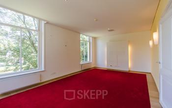 Spacious office with large windows and a red carpet at Prinsen Bolwerk 1, suitable for office space rental near Haarlem Centraal Station.