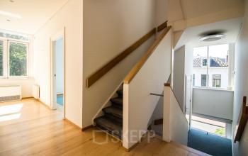 Bright interior view of an unfurnished office space available for rent at Prinsen Bolwerk 1, Haarlem Centraal Station, featuring wooden floors, large windows, and a staircase.