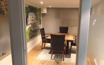 Modern office space rental at Staten Bolwerk 1, Haarlem Centraal Station, featuring a wooden table with chairs and ambient lighting.