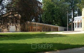 Exterior view of office space rental located at Staten Bolwerk 1, Haarlem Centraal Station, Haarlem, featuring a modern building with large windows surrounded by lush greenery.