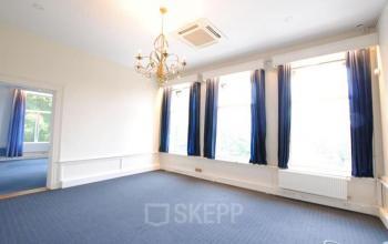 Office space rental at Staten Bolwerk 1 in Haarlem Centraal Station, featuring large windows, blue carpet, and a chandelier.