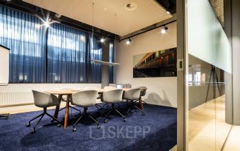 Professional office space rental at Kennemerplein 6-14, with a well-lit conference room featuring modern furniture and large windows in Haarlem Centraal Station area.