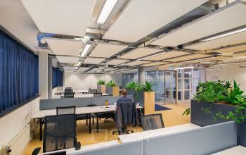 Modern office space at Kennemerplein 6-14, Haarlem Centraal Station, with desk partitions, chairs, and greenery, suitable for office space rental.